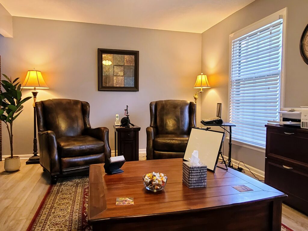 Two brown leather chairs with a table and office equipment in a light colored room.